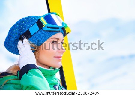 Closeup portrait of cute skier girl looking far away, wearing special sportive mask and holding in hands ski equipment, active lifestyle, enjoying winter vacation concept