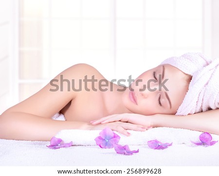 Beautiful woman with closed eyes lying down on massage table, enjoying day spa, luxury beauty salon, healthy lifestyle