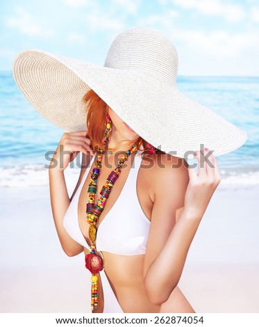 Sexy woman on the beach, fashion model posing on seashore, wearing a big hat, and covers her face, fashionable summer photo shoot