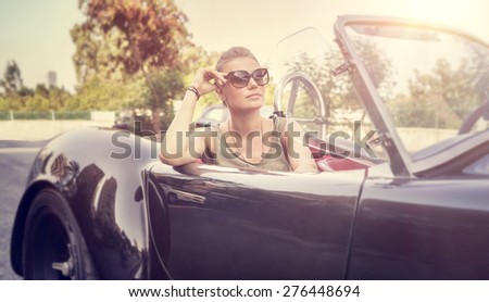 Beautiful woman sitting in cabriolet, sexy female enjoying trip on luxury modern car with open roof, fashionable lifestyle concept