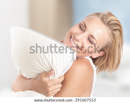 Happy girl enjoying white soft pillow, playing with downy cushion, closed eyes of pleasure, having fun at home, happy joyful youth lifestyle