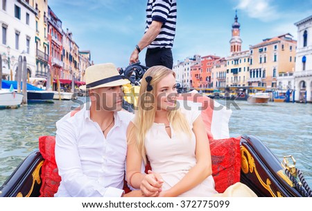 Young happy couple riding on a gondola on Grand Canal in Venice, spending honeymoon in Italy, Europe