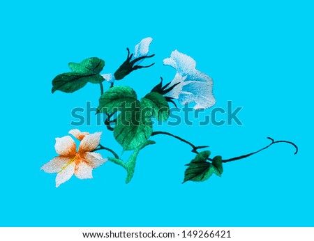 Silk flower sewing by hand on blue background.