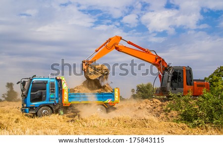 Industrial truck loader excavator moving earth and uploading into a truck.
