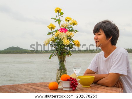 Asian man relaxing on the decorated table beside the sea.