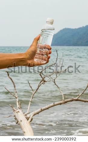 Drinking water bottle holding by hand   beside the sea.