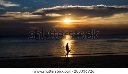 Silhouette of human  walking on the beach with sunset view.