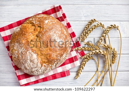 crusty bread with wheat on wooden table
