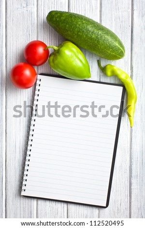 blank recipe book with vegetable on kitchen table