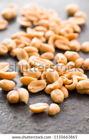 Salted roasted peanuts on black table.