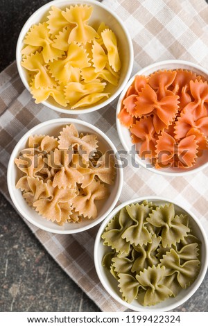 Farfalle pasta. Colorful italian pasta in bowl on old kitchen table.