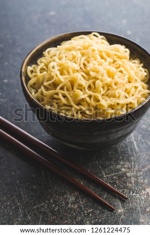 Cooked chinese instant noodles in bowl and chopsticks.