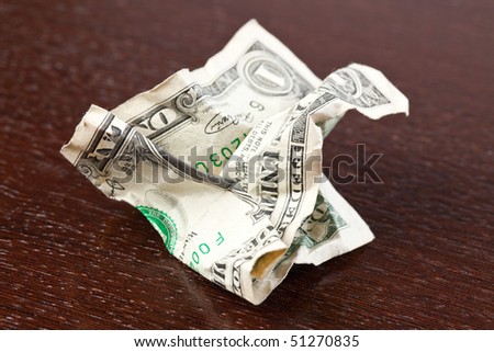 wrinkled dollar on wooden table
