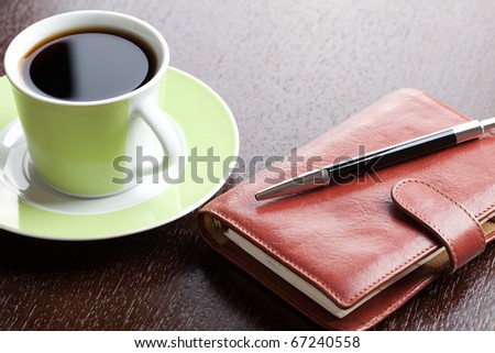 pen on diary and coffee mug