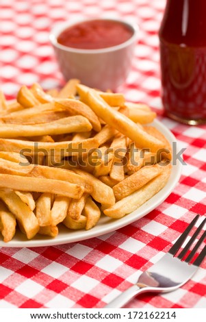 french fries on plate with ketchup on checkered tablecloth