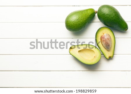 top view of halved avocados on wooden background