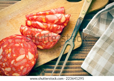 sliced chorizo salami with fork on cutting board