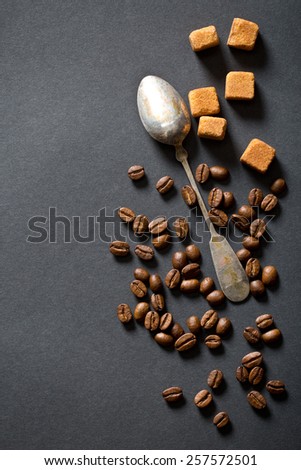 coffee beans, sugar and silver spoon on black background