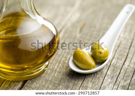 green olives and olive oil on old table