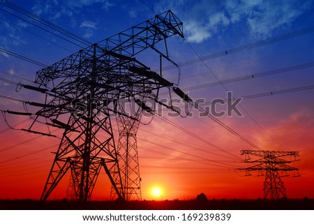 Many high voltage tower under the setting sun exposure in the field