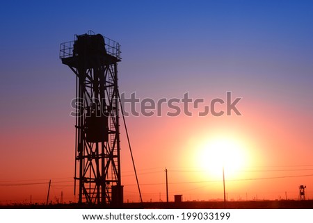 A the isolated tower pumping unit is operating under the sunset