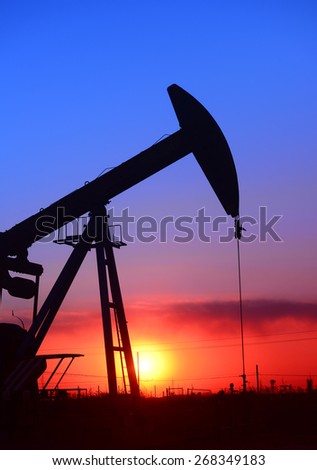 A pumping unit is operations under the setting sun, close-up