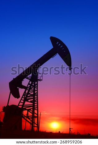 A pumping unit is operations under the setting sun, close-up