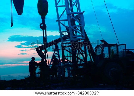The silhouette of oil pump in the work, in the evening