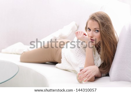 Young blonde woman lying on the sofa. She smells perfume on your wrist