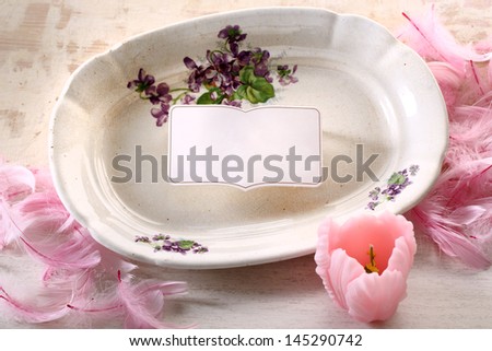 Plate with painted flowers on beige background with frame and woody tulip and bird feathers