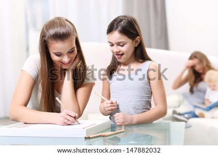 Two girls write something for a glass table