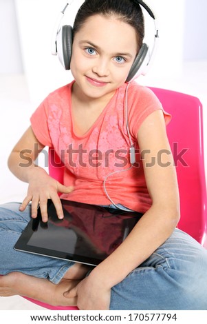E-learning  / Young girl in a pink shirt with earphones and a tablet