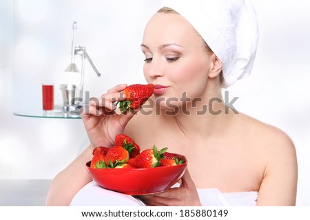 Strawberry woman . Attractive girl with a bowl of ripe strawberries relaxes in the living room.