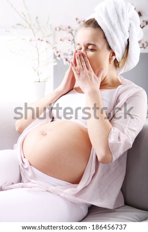 Tired in pregnancy . Pregnant woman yawns resting on the sofa