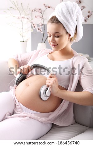 Music in pregnancy  A pregnant woman lets the music for belly relaxing on a sofa
