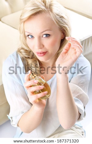 Sensual perfume - woman test perfume on her wrist .Form of a beautiful blonde holding in his hand a bottle of perfume