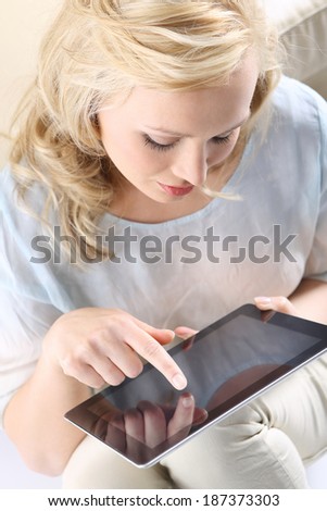 Girl checking e-mail . Figure of a young, beautiful blonde with a digital tablet, the woman touches the screen,