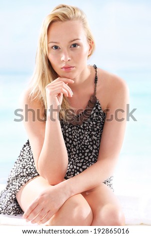 Photo of seaside holidays. Woman in summer dress sitting on a deck chair and enjoy the sun bath