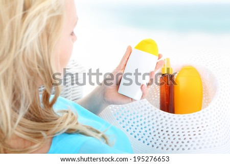 Sun care - cosmetics for tanning . A woman sitting in a basket and reads the beach sun care