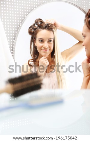 Hairstyling. Changing colors  Woman with hair standing in front of a mirror. Changing hair color. Full colored hair.