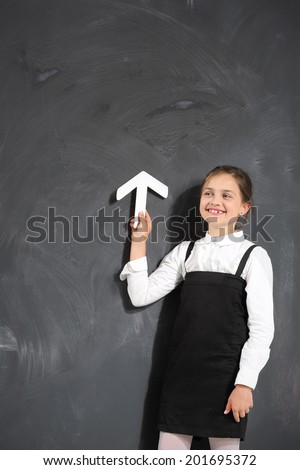 A child at the blackboard . Cute little girl standing by a black school board