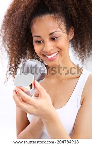 Dark skinned woman reads the face cream. Young dark skinned girl smiling while looking under the microscope the face cream
