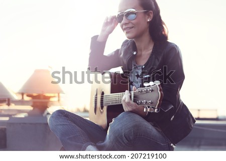 Girl with acoustic guitar . Woman in the sun playing acoustic guitar.