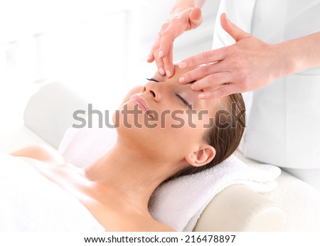 Beautician beautiful woman massaging her temples .Attractive brunette woman in spa salon.