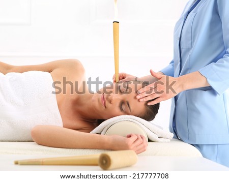 Spa - ear candling .Woman relaxes in the study of natural medicine. ear candling treatment