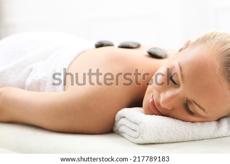 Hot stone massage, a woman in spa salon. Attractive blonde woman in spa salon on massage relaxation basalt stones
