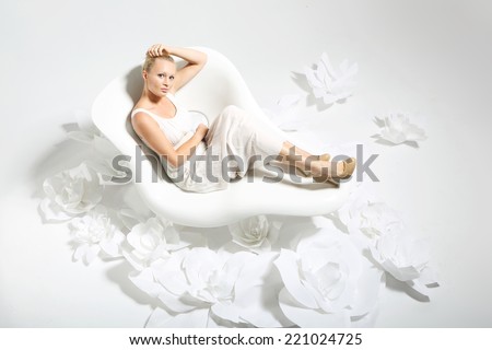 Beautiful woman in flowers .Beautiful young woman sitting on a white chair surrounded by stylish white flowers