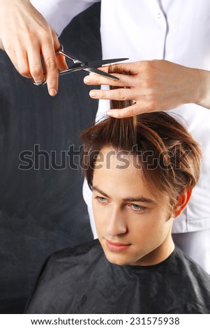 Hairdresser cuts hair young boy.Portrait of a young white boy while cutting hair in the hair salon