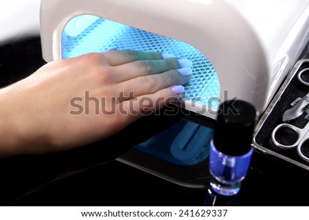 Hybrid manicure, uv lamp, nail plate curing. Beauty salon, manicure, woman at the beautician,