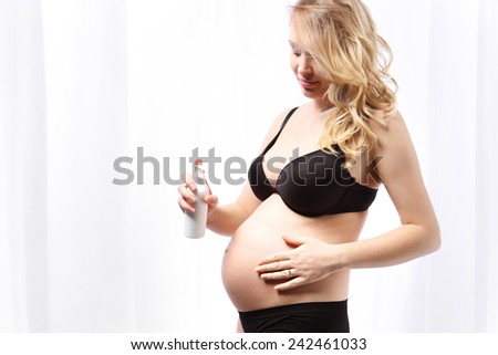 Body care during pregnancy. Pregnant woman belly lubricates balm for stretch marks